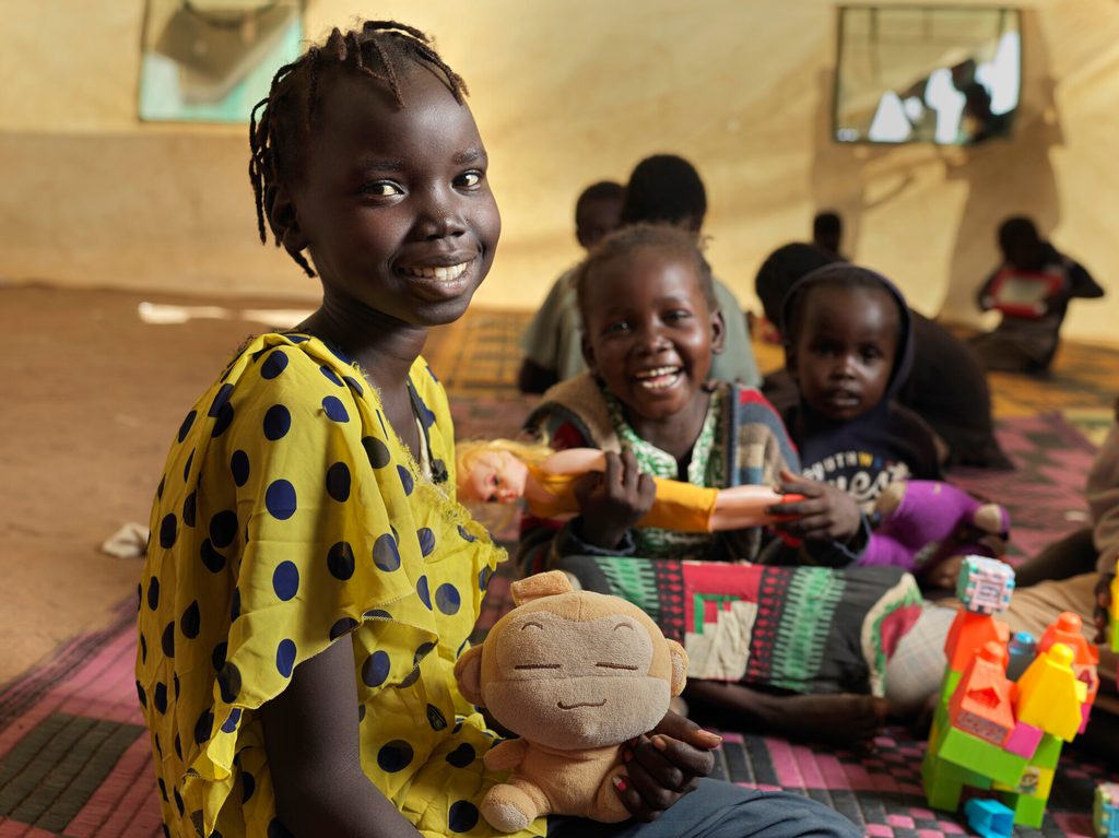 12-year-old Lena from Sudan sits in a tent with her friends.